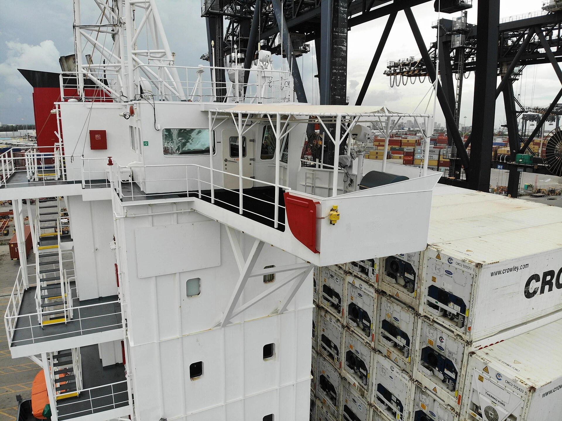 Bridge wing of a cargo vessel with port cranes in the background